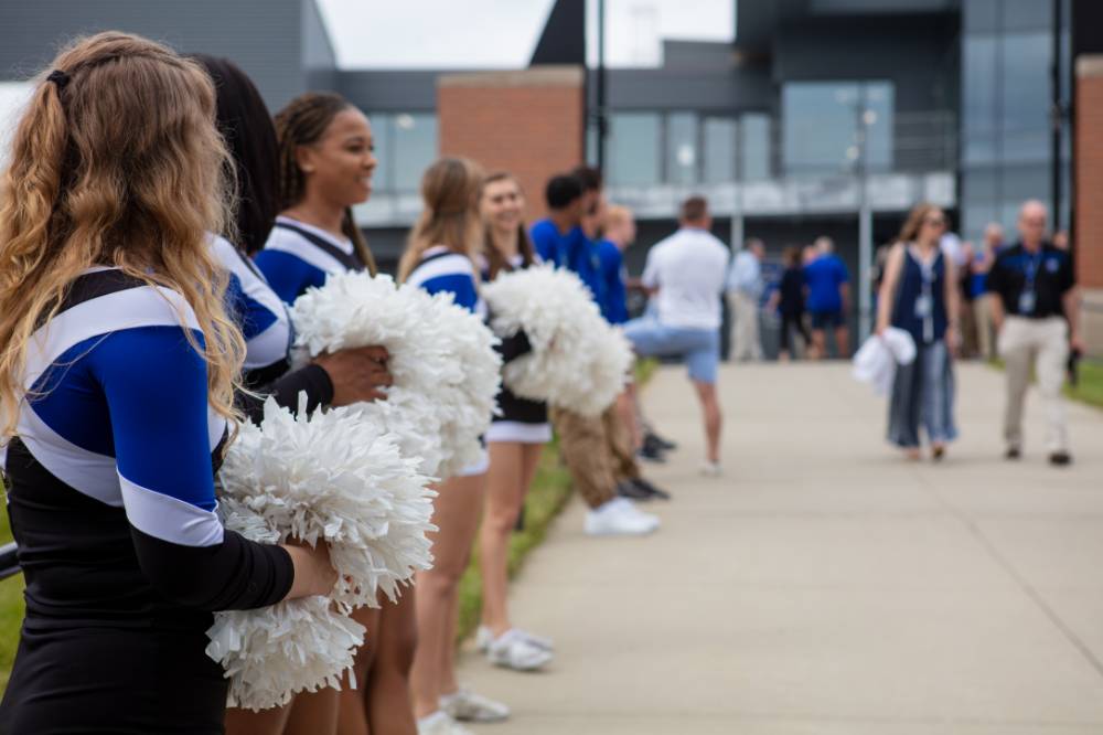 Cheerleaders holding pom poms, standing in a line at the Jamie Hosford Football Center dedication.